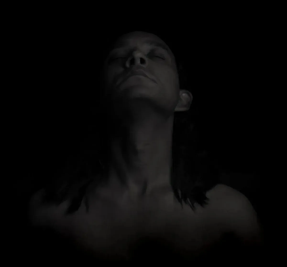 Abstract low-key portrait of a man emerging from darkness under sculpted studio light