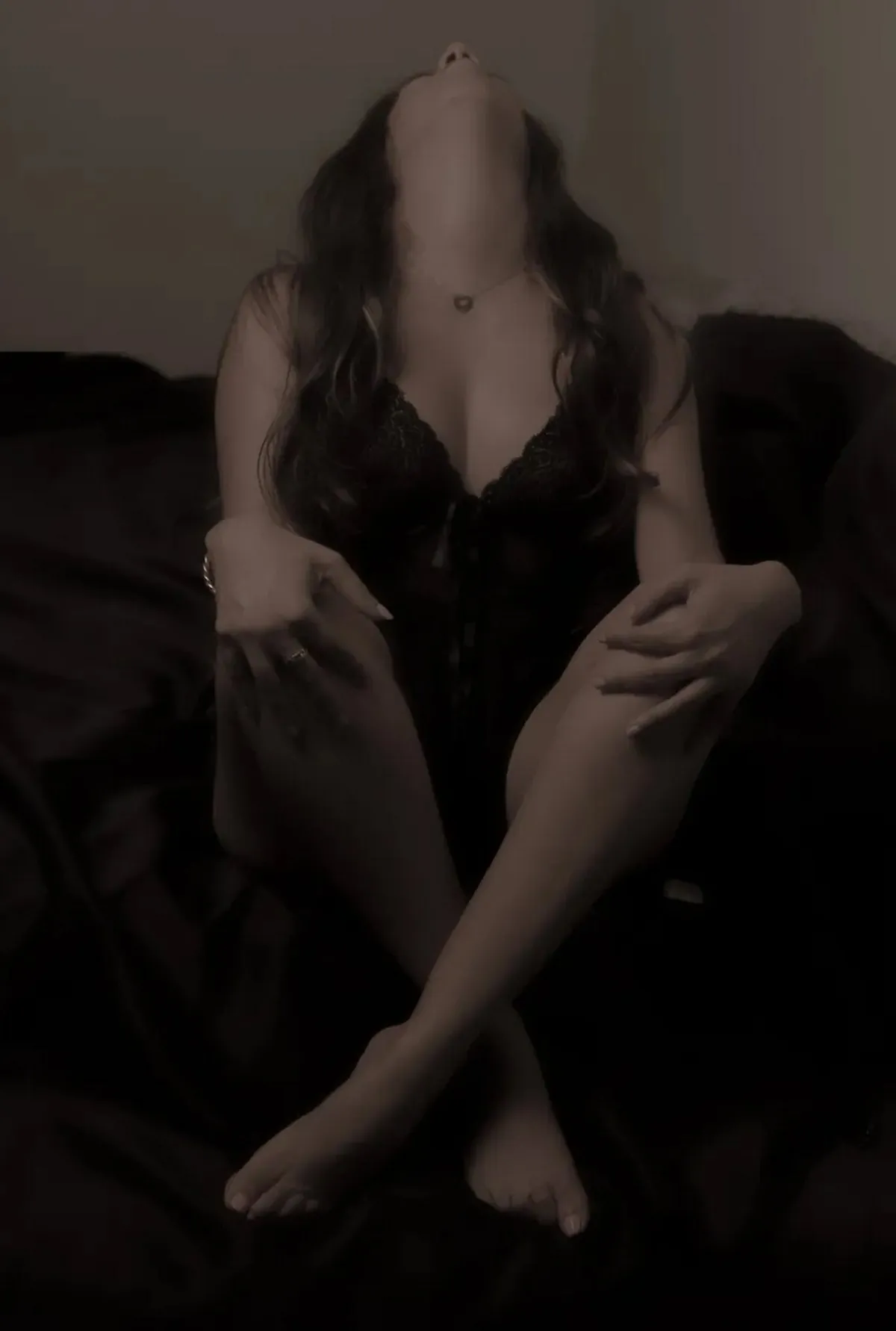 Anonymous seated boudoir portrait focusing on body shape, hands and shadow