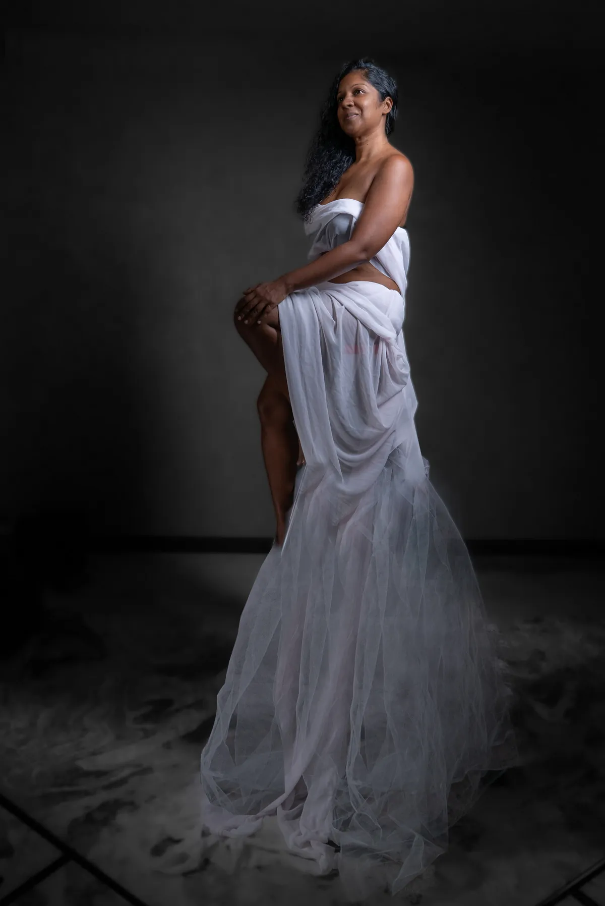 Full-length creative portrait of Natacha Boodhoo seated in a flowing white dress