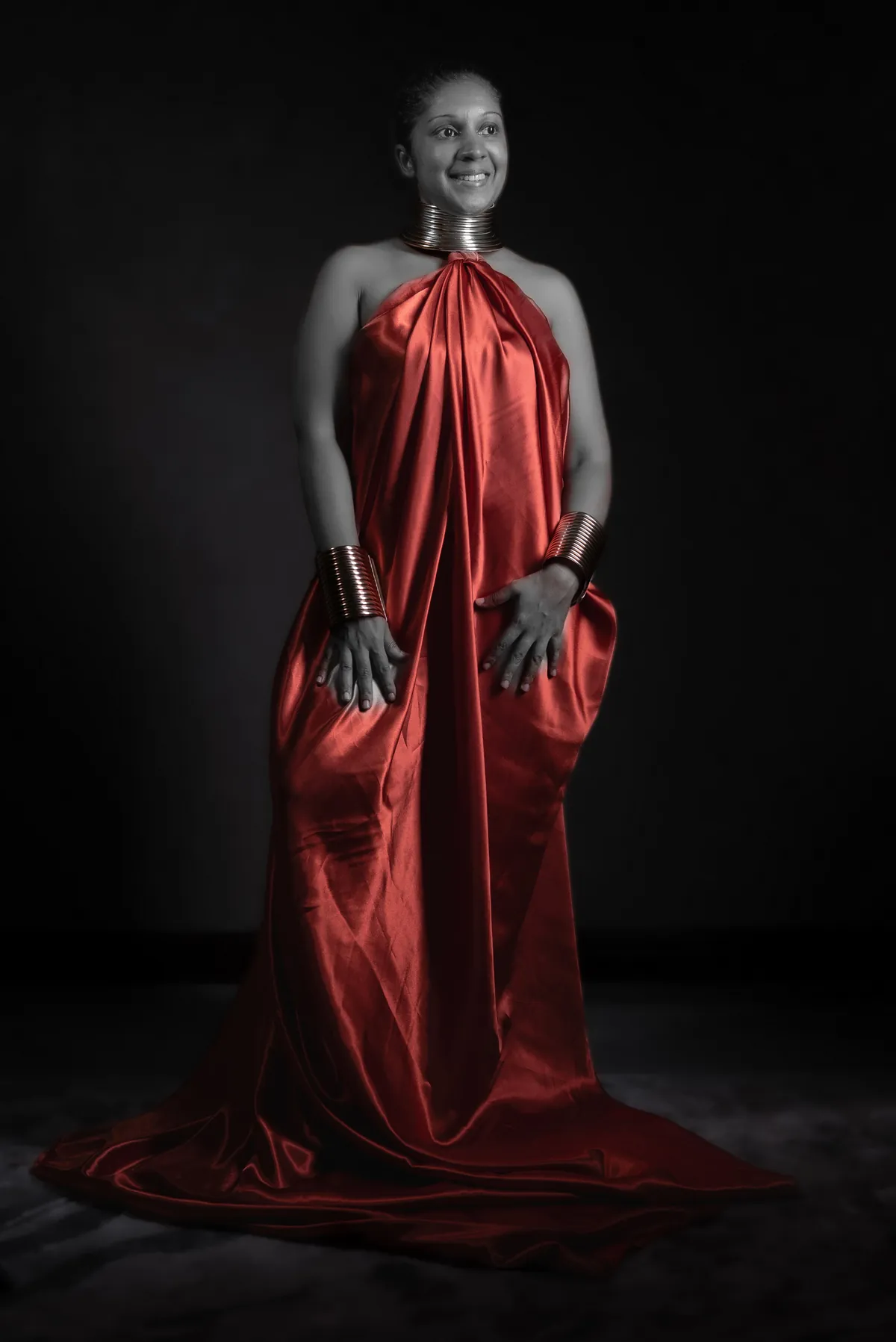 Full-length creative studio photograph of artist Natacha Boodhoo wearing a flowing red dress