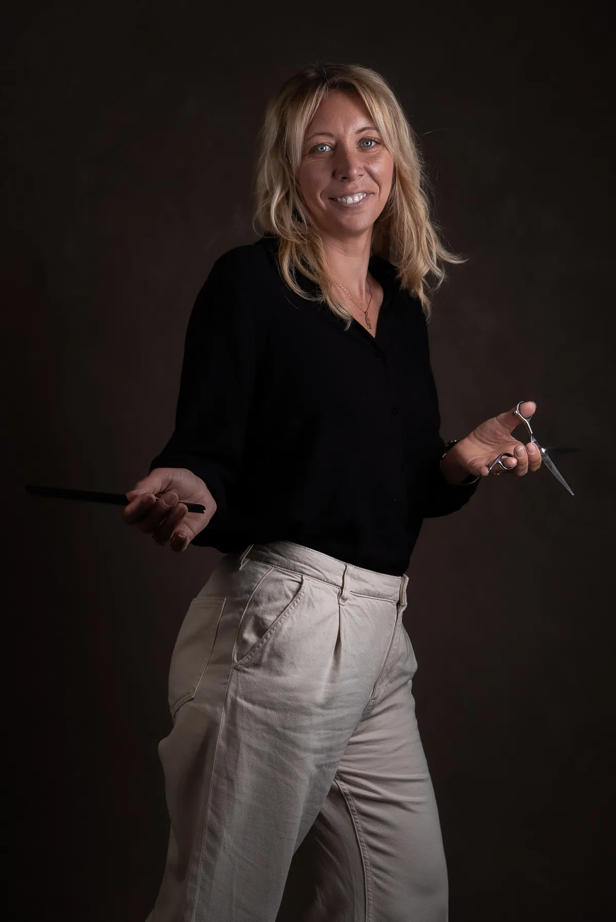 Full-length creative studio photograph of Ophélie Sapin holding a comb and scissors