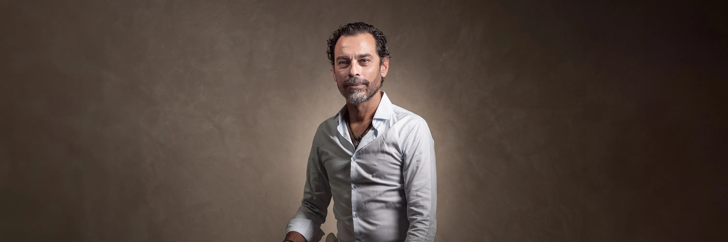 Portrait en studio professionnel d'un homme assis sur un fond neutre et chaleureux