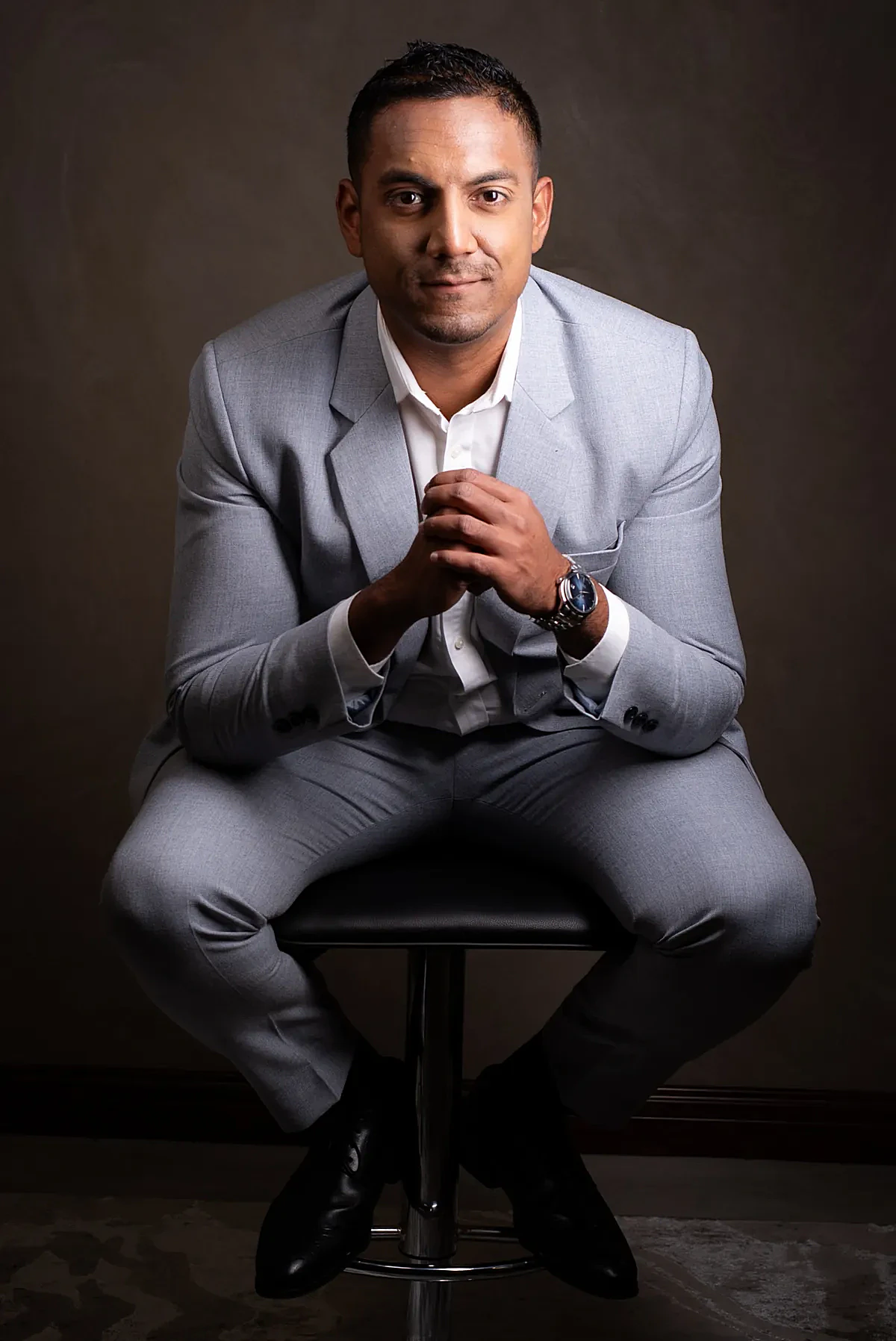 Portrait professionnel complet du corps de Sharma Soneechora assise dans un costume gris