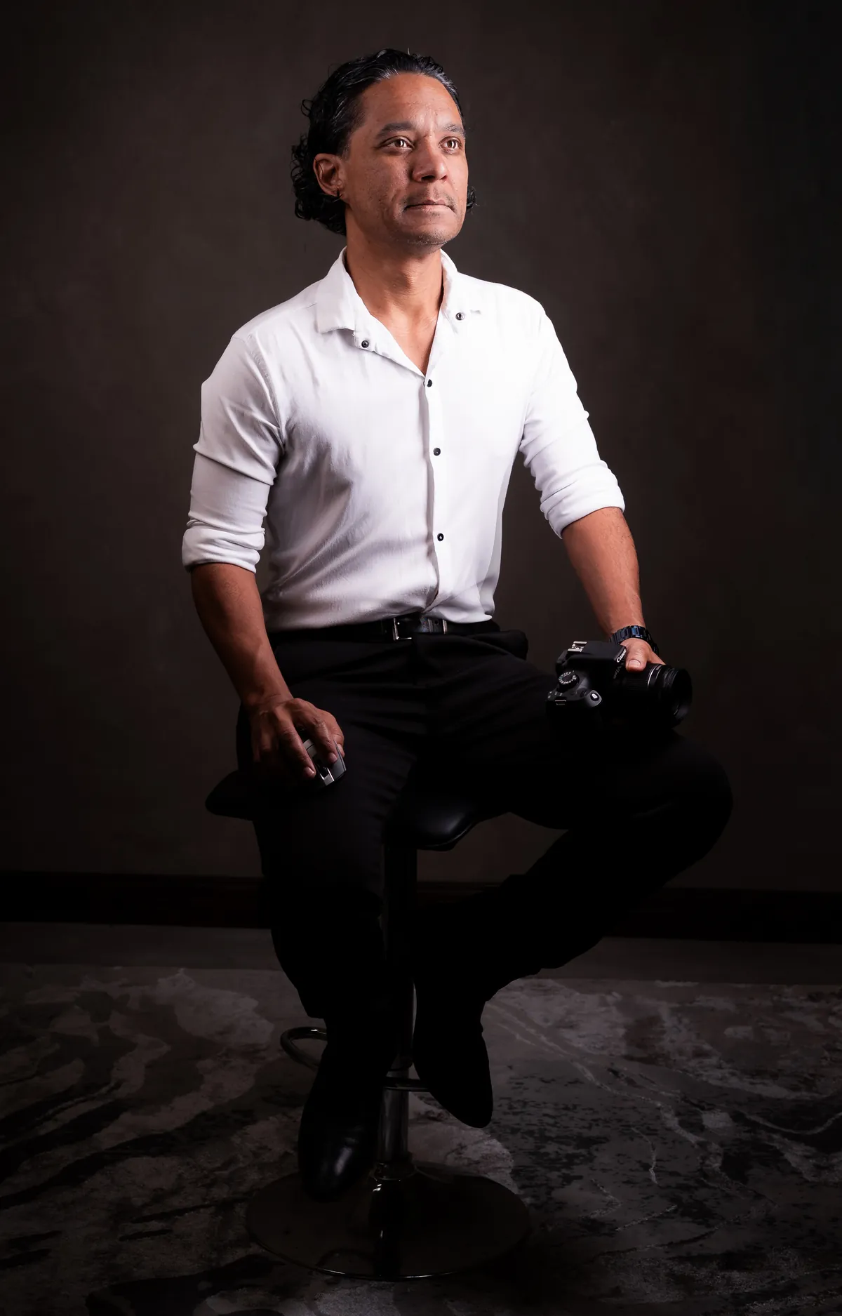 Kurt François assis dans son studio de photographie tenant un appareil photo