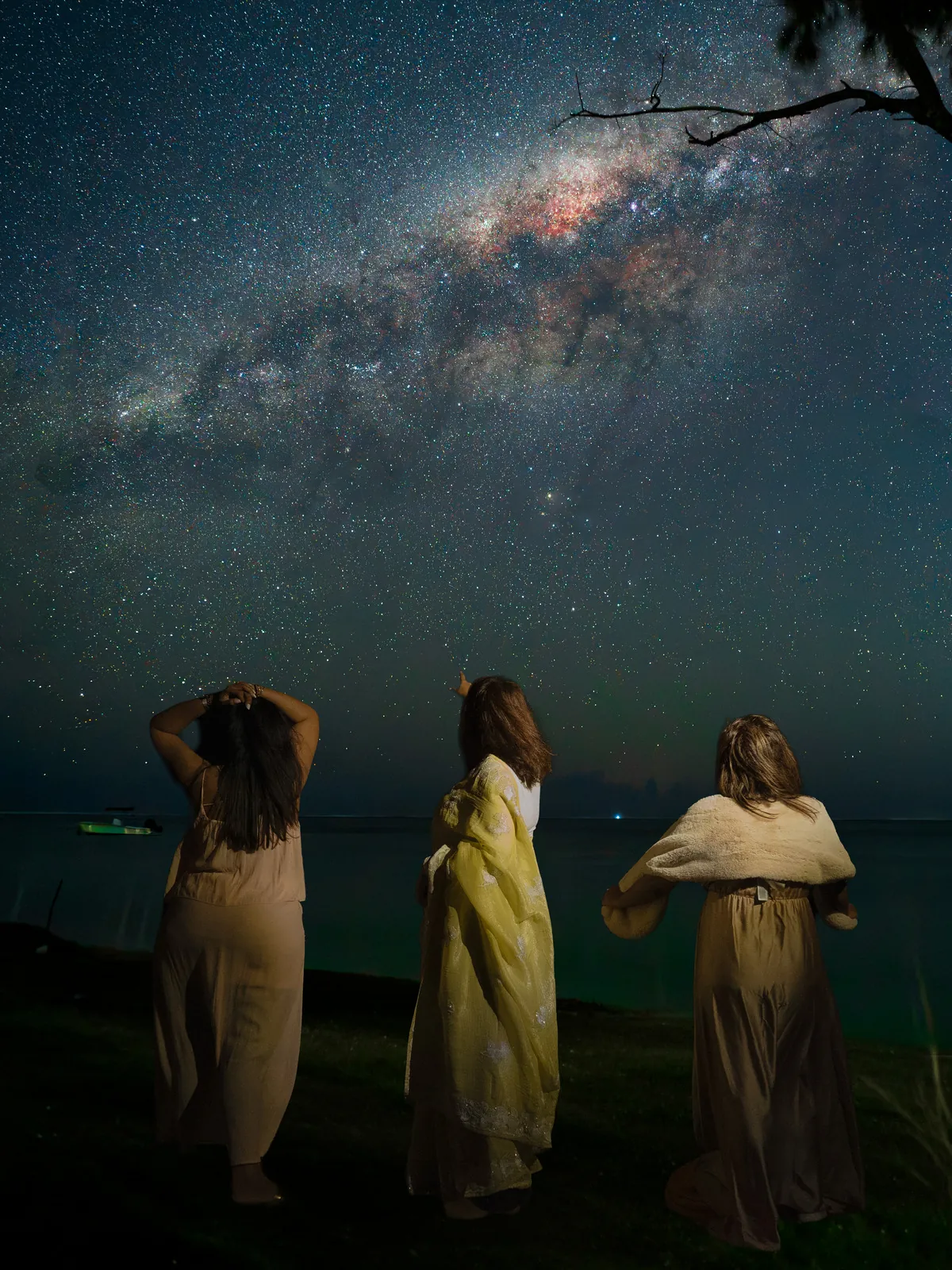 Three women photographed from behind beneath the Milky Way during a creative night portrait session