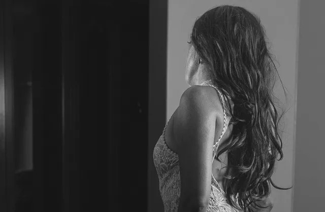 Fille aux cheveux longs à genoux avec robe blanche serrée posant pour une séance photo de boudoir