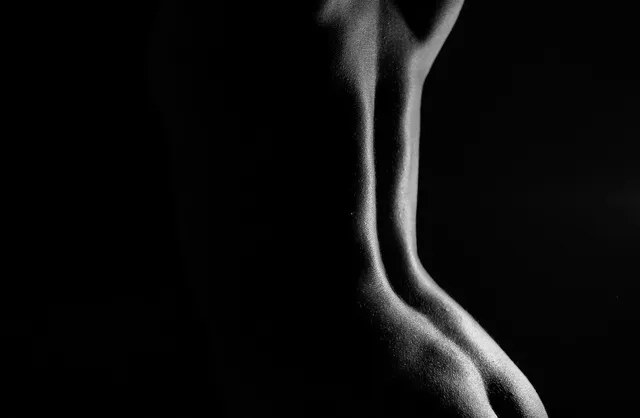 Graceful nude curves of woman body in monochrome photography revealing her back and ass