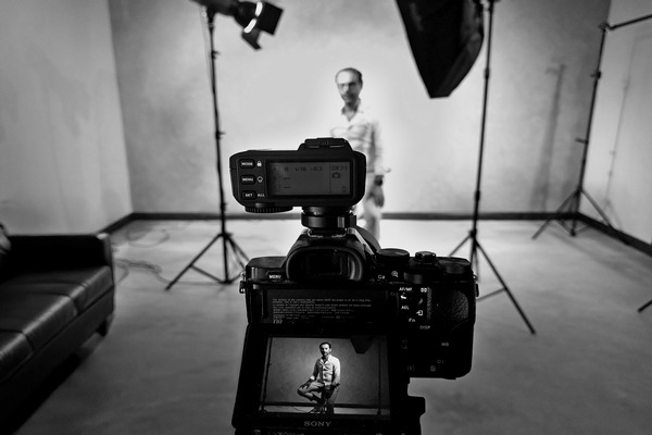 DSLR camera capturing a male model at Nude Art studio with visible live preview on screen